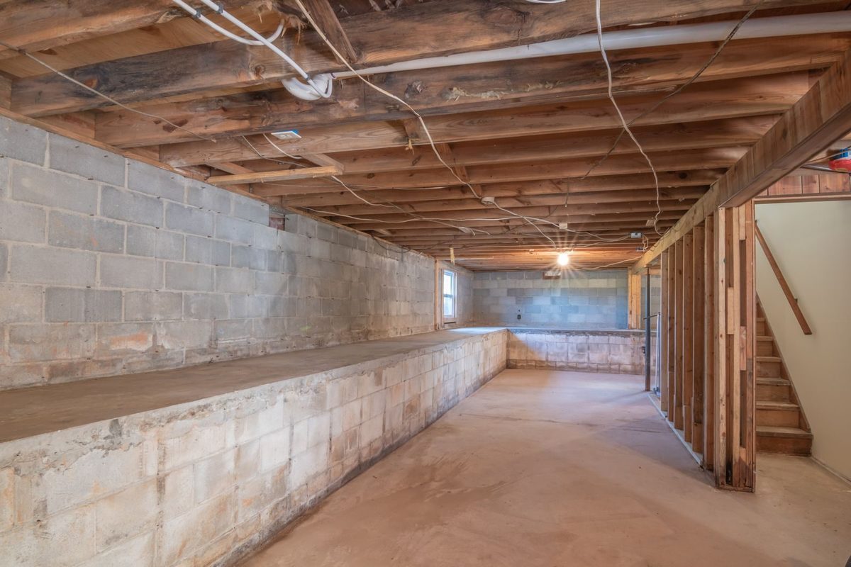 Unfinished basement with exposed joists after water damage in Plano, TX